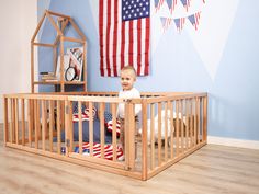 a baby in a wooden crib with an american flag on the wall behind it