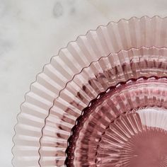 a pink glass bowl sitting on top of a white marble countertop next to a wall