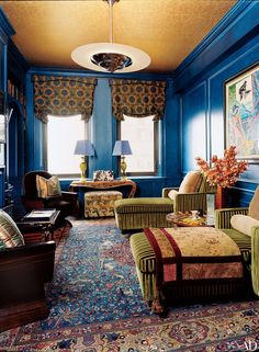 a living room with blue walls and colorful furniture on the carpeted floor, along with large windows