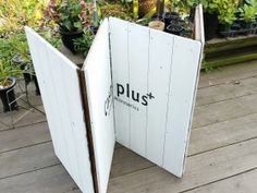 an open book sitting on top of a wooden floor next to potted planters