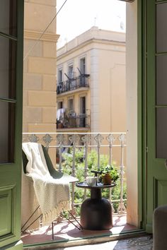 an open door to a balcony with a chair and table in the foreground, outside