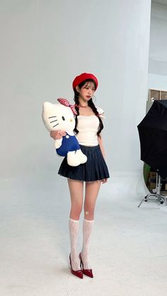 a woman holding a hello kitty stuffed animal in a studio with an umbrella behind her