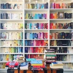 a room filled with lots of books on top of a wooden table next to a book shelf