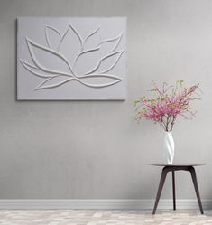 a vase filled with pink flowers sitting on top of a table next to a painting