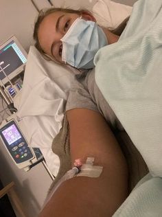 a woman laying in a hospital bed wearing a face mask with an iv attached to her arm