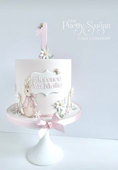 a pink and white cake with an animal on the top is sitting on a pedestal