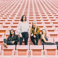 three women sitting in rows of empty stadium seats