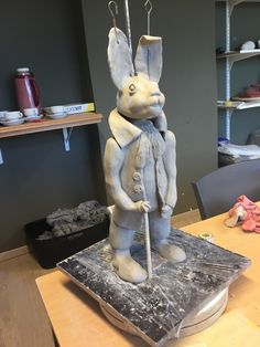 a statue of a rabbit holding a cane on top of a table in a room