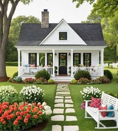 a white house with flowers in the front yard and steps leading up to it's porch