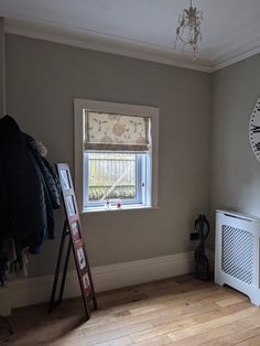 an empty room with a window, radiator and coat rack in the corner