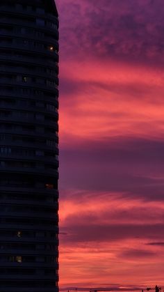 a tall building sitting next to a large tower under a purple sky with clouds in the background