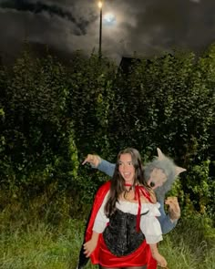 a woman and child dressed up in costumes posing for a photo at night with the moon behind them