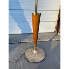 a lamp that is on top of a metal base with a wooden pole in the middle