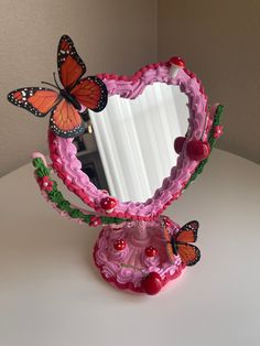 there is a pink mirror with butterflies on it and cherries in the bottom half