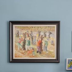 a painting hanging on the wall next to two pictures and a framed photo with people in it