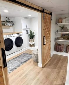 a washer and dryer in a room with wooden floors, white walls and open doors