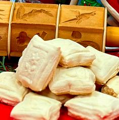 several pieces of white chocolate sitting on top of a red table next to wooden boxes