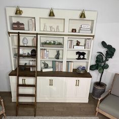 there is a ladder leaning against the bookshelf in this living room with white cabinets