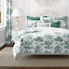 a bed with green and white comforters in a bedroom next to a chandelier