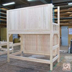 a wooden bed frame in the middle of a room with other woodworking equipment around it