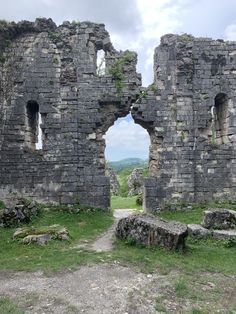 an old stone building with two windows and a dirt path leading to the other side