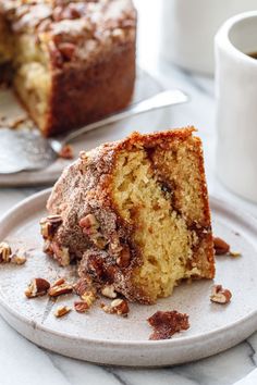 a piece of cake sitting on top of a white plate next to a cup of coffee