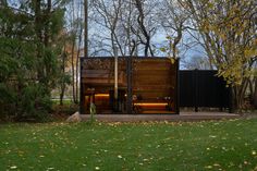 a small wooden structure sitting on top of a lush green field next to trees and bushes