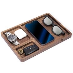 a wooden tray with sunglasses, watch, keys and other items in it on a white background