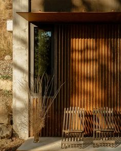 two wooden benches sitting next to each other near a building with metal slats on it