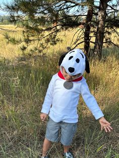 a little boy that is standing in the grass with a stuffed dog on his head