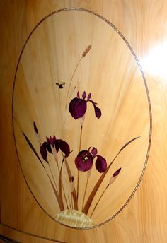 a vase with purple flowers in it sitting on a wooden table next to a wall