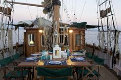 the dining table is set for two on the deck of a boat in the ocean