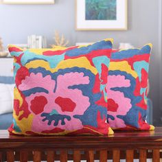 two colorful pillows sitting on top of a wooden table