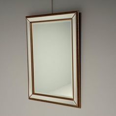 a mirror hanging on the wall with a light attached to it's side,