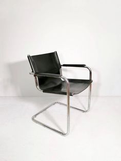 a black leather chair sitting on top of a white floor next to a metal frame