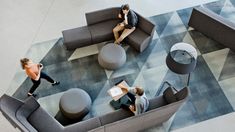 three people are sitting on couches in an office lobby with checkered flooring