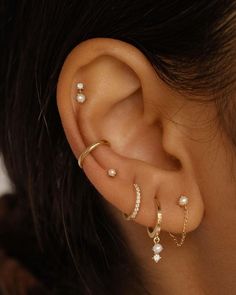 a woman wearing three different types of ear piercings