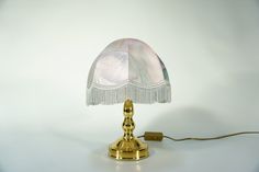 a lamp that is sitting on top of a white surface with a cord attached to it