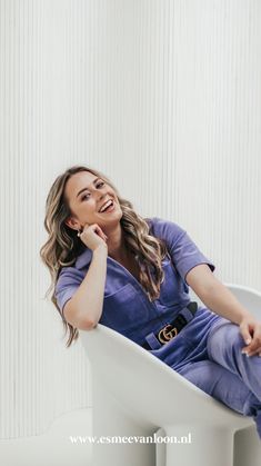 a woman sitting in a chair with her hand on her chin and smiling at the camera