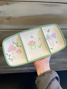 a person holding three plates with different designs on them, one is green and the other is white