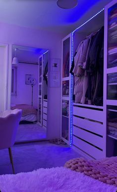 a bedroom with purple lighting and a bed in the corner, next to a closet full of clothes