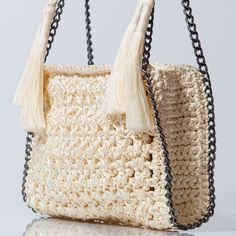 a crocheted bag with tassels hanging from it's handle and chain