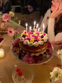 a woman sitting in front of a cake with lit candles