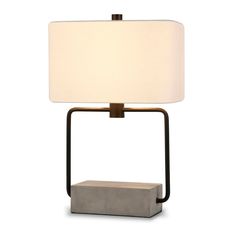 a lamp that is sitting on top of a table with a white shade over it