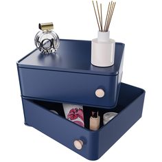 two blue boxes with different types of items in them and one has a candle on top