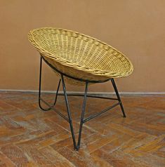 a wicker basket sitting on top of a black metal frame stand in front of a tan wall