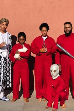 a group of people standing next to each other wearing red outfits and holding baseball bats