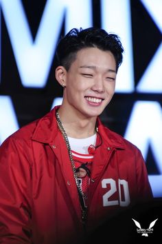 a young man smiling and wearing a red jacket