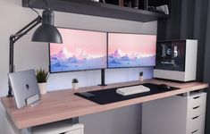 two computer monitors sitting on top of a wooden desk