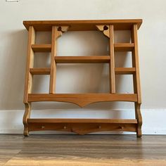 a wooden shelf with two open shelves on the top and bottom, against a white wall